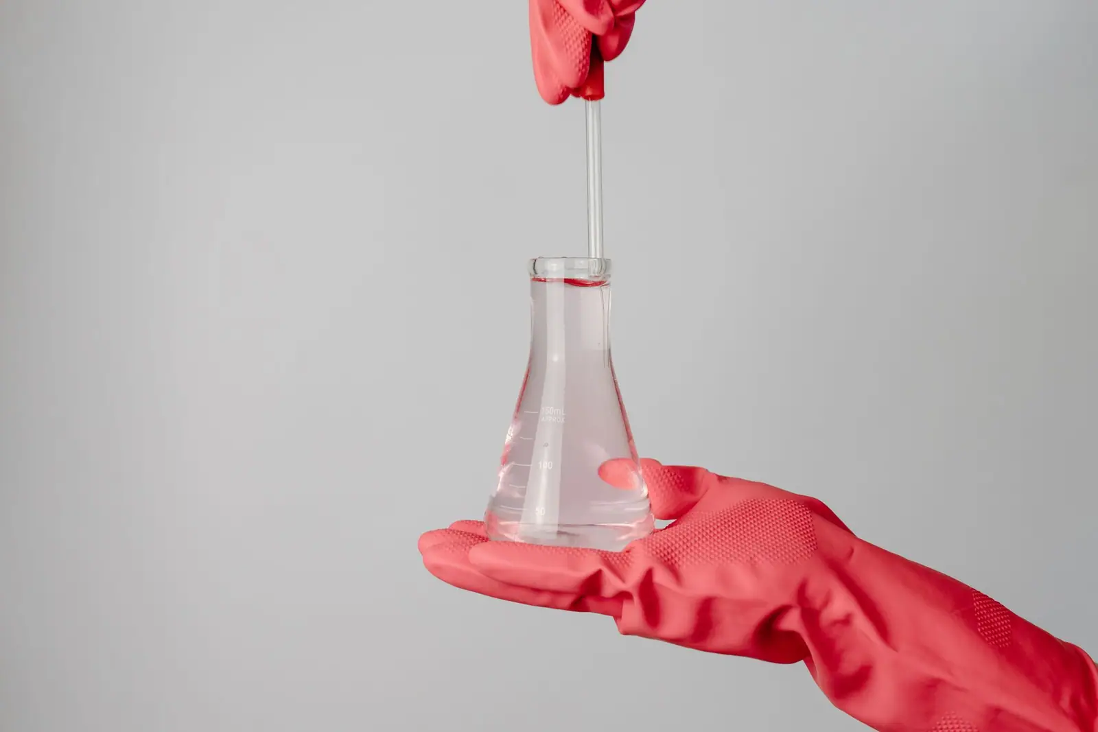 A gloved hand holding a flask with a water sample