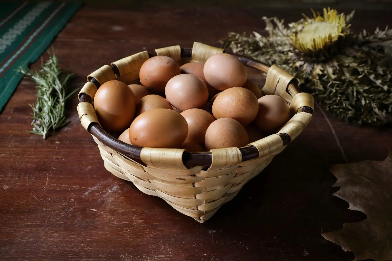 A woven basket of brown eggs on a wooden table